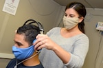 an audiology technician at Naval Branch Health Clinic Jacksonville’s occupational health clinic, conducts a hearing exam with Airman Diosney Moraga