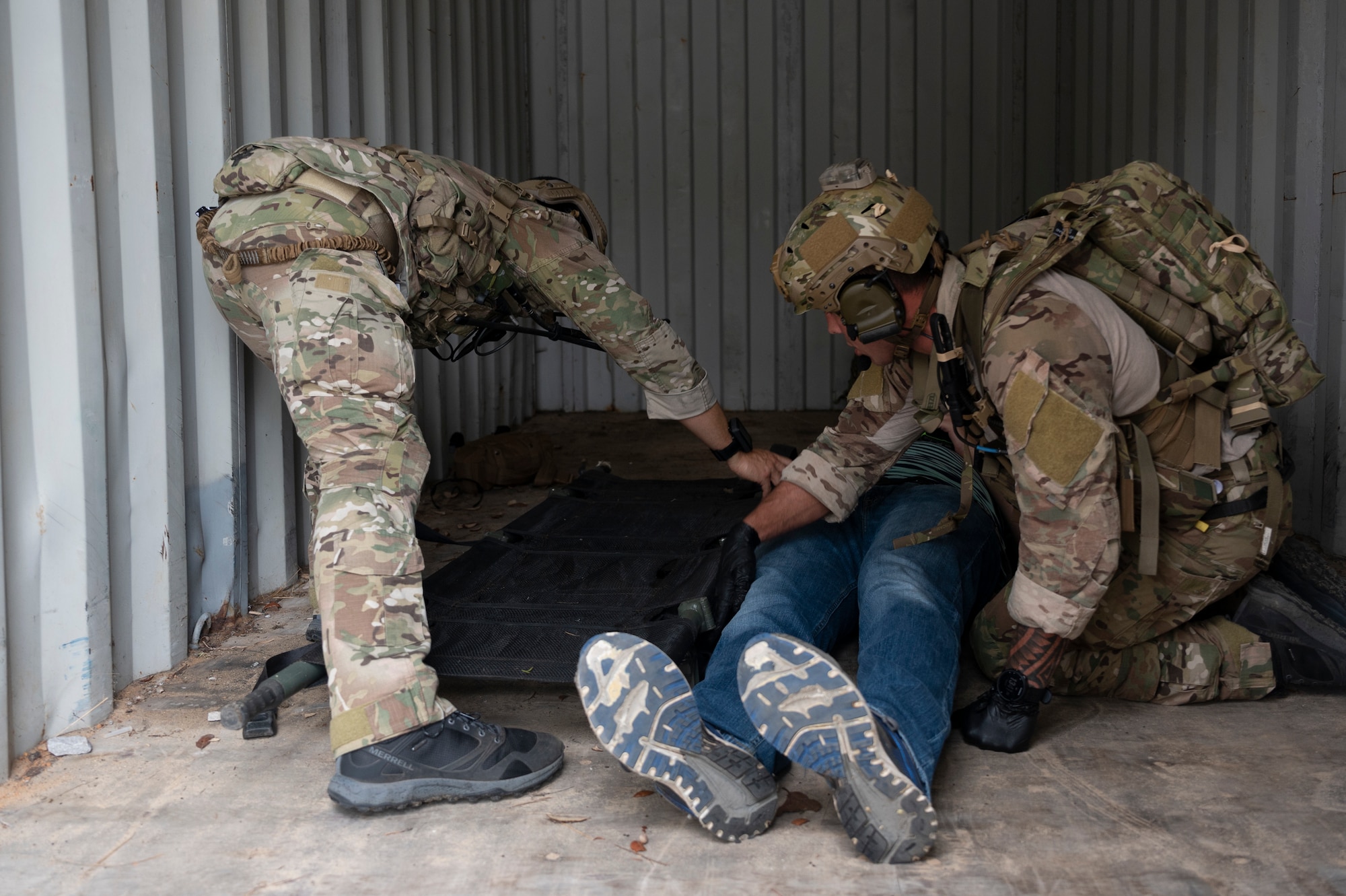 We look at the bottoms of the shoes of a patient as he is flanked by two Special Tactics Operators working as a team to move the injured patient onto a stretcher.