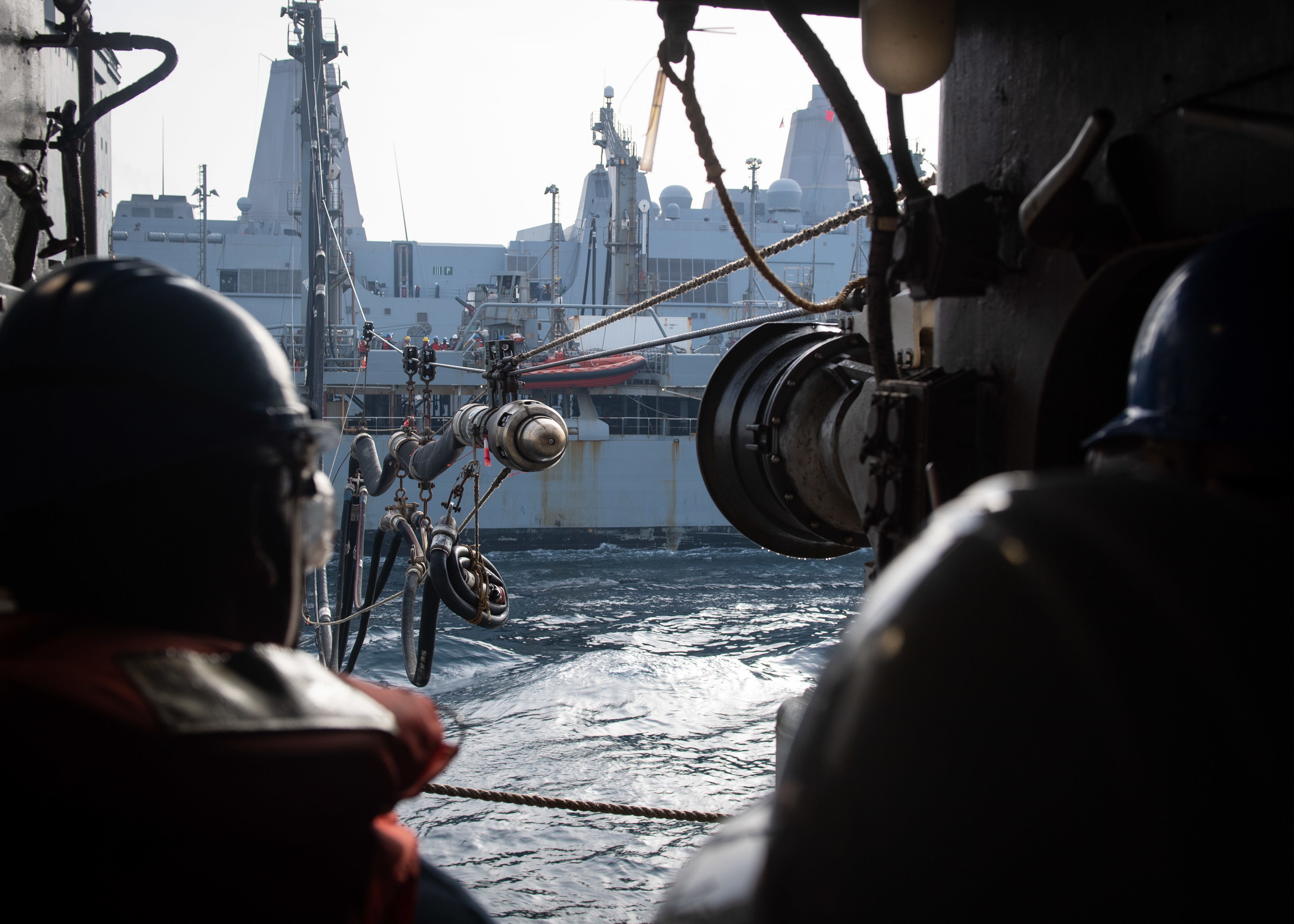 Sailors assigned to the amphibious dock landing ship USS Oak Hill (LSD 51) observe as a fuel line from the fleet replenishment oiler USNS Walter S. Diehl (T-AO 193) approaches Oak Hill during a replenishment-at-sea, April 4, 2020.