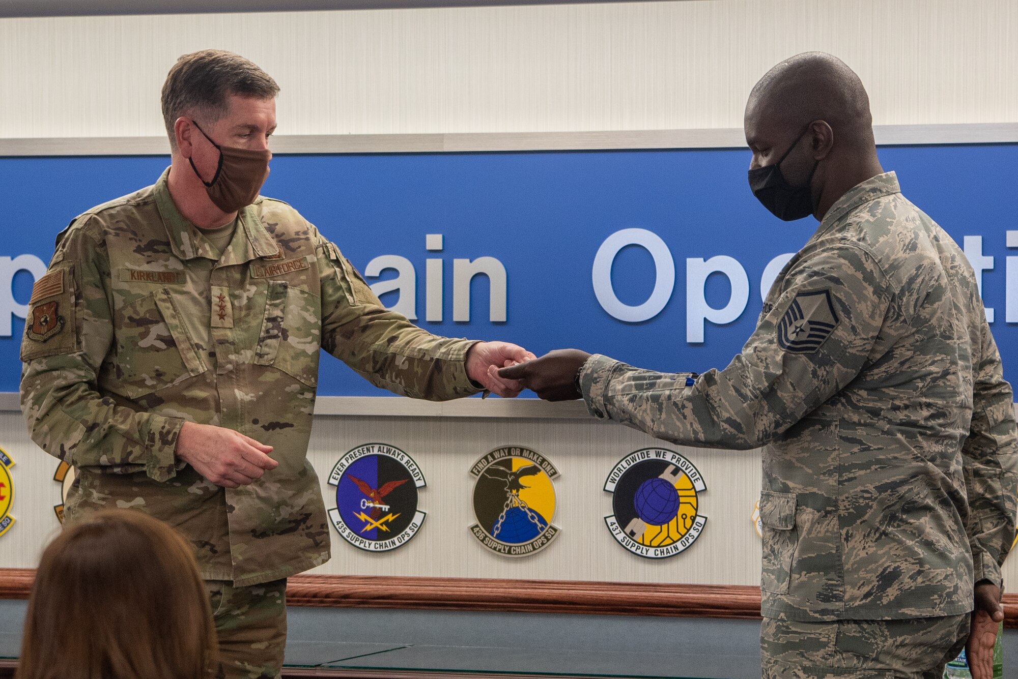Master Sgt. Kweshi Raymond (Q), NCOIC C-130 Sustainment with the 436th Supply Chain Operations Squadron receives a coin from Air Force Lt. Gen. Gene Kirkland, Air Force Sustainment Center commander on Oct. 19.