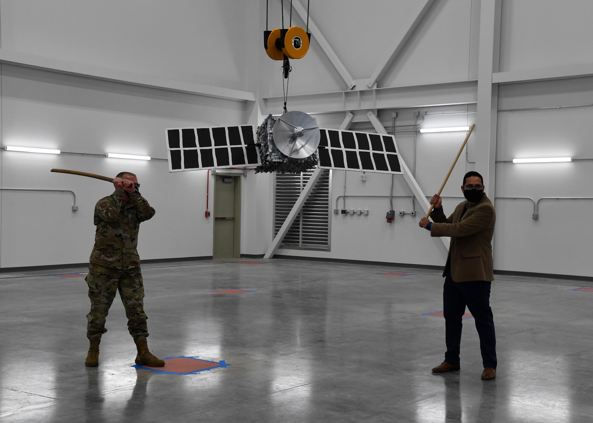 Director of the Air Force Research Laboratory Space Vehicles Directorate, Col. Eric Felt (left) and Benjamin Urioste, research engineer, prepare to break the satellite piñata, following the ribbon cutting ceremony to celebrate the opening of the directorate’s Deployable Structures Laboratory at Kirtland Air Force Base, New Mexico, Oct. 29, 2020. (U.S. Air Force photo by Airman 1st Class Ireland Summers)