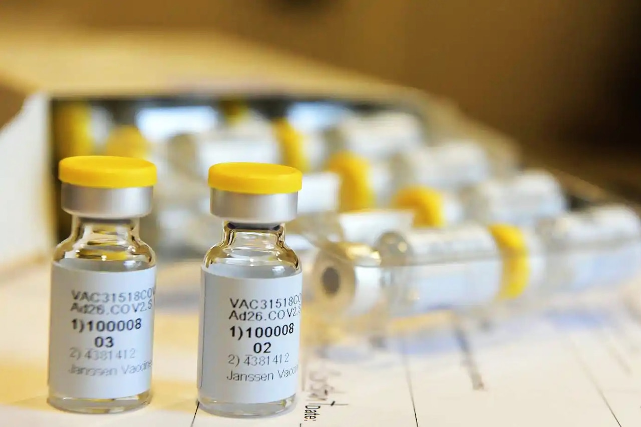 Two containers of a potential vaccine are in the forefront while several more are in the background in a tray.