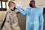 A Soldier has his temperature checked after arriving at Joint Base San Antonio-Kelly Field Annex from Fort Jackson, Mississippi, on a chartered flight. Checking for symptoms is one of the many preventive measures in place to limit the spread of the coronavirus.