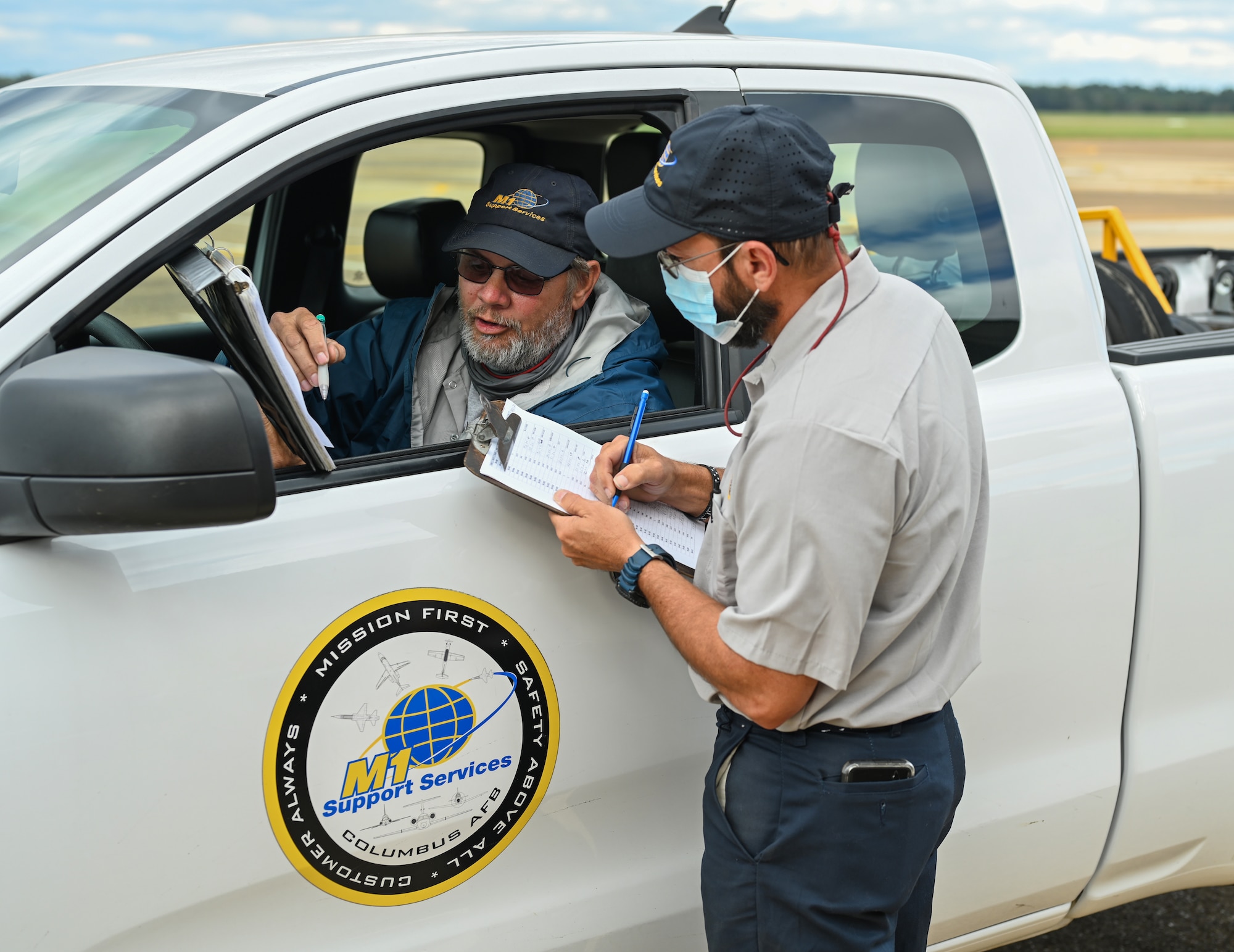 Jonathan McCoy (right) , M1 Support Services T-1A Jayhawk lead mechanic, and another M1 Support Services T-1A Jayhawk mechanic discuss the flying schedule for the T-1A Jayhawks on Oct. 29, 2020, at Columbus Air Force Base, Miss. In fiscal year 2019 alone, 14th Flying Training Wing pilots flew 10,784 sorties in the T-1A Jayhawk.  (U.S. Air Force by Airman 1st Class Davis Donaldson)