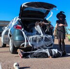 Airman, on ground, plays the webbed victim during the trunk decorating contest.