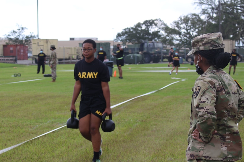 Pvt. Trinity Beckford carries two 40-pound kettle bells as part of the Army Combat Fitness Test as Sgt. Latiria Stewart observes during training on the ACFT in Belle Chasse, Louisiana October 25, 2020.