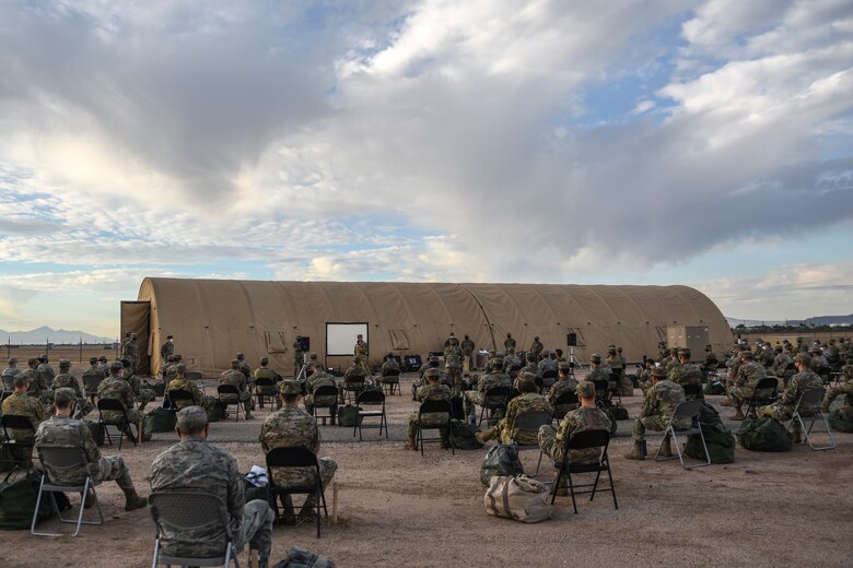 A photo of Airmen sitting in chairs and listening to a brief.