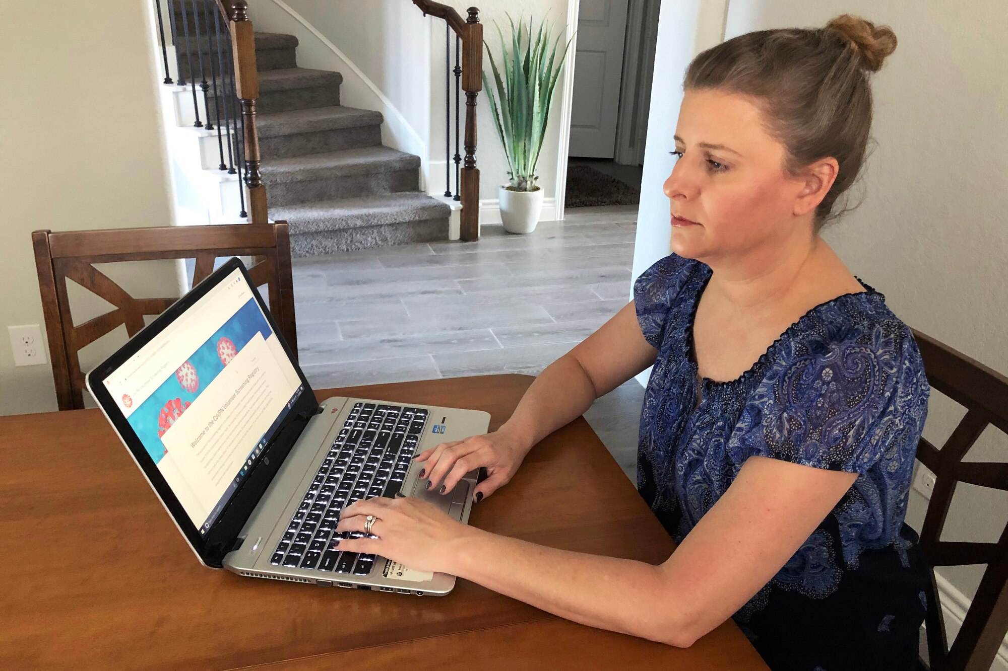 A woman sits at a table and works on a computer.