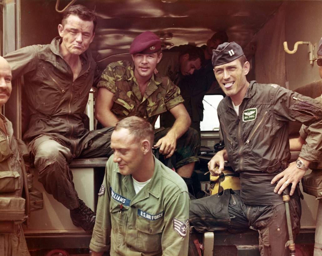 Five men hang out together at the opening of a makeshift building.