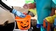 Airman Jonnica Blaylock, a Barksdale volunteer, places candy in a child’s bucket during the Trunk or Treat event at Barksdale Air Force Base, La., Oct. 31, 2020.