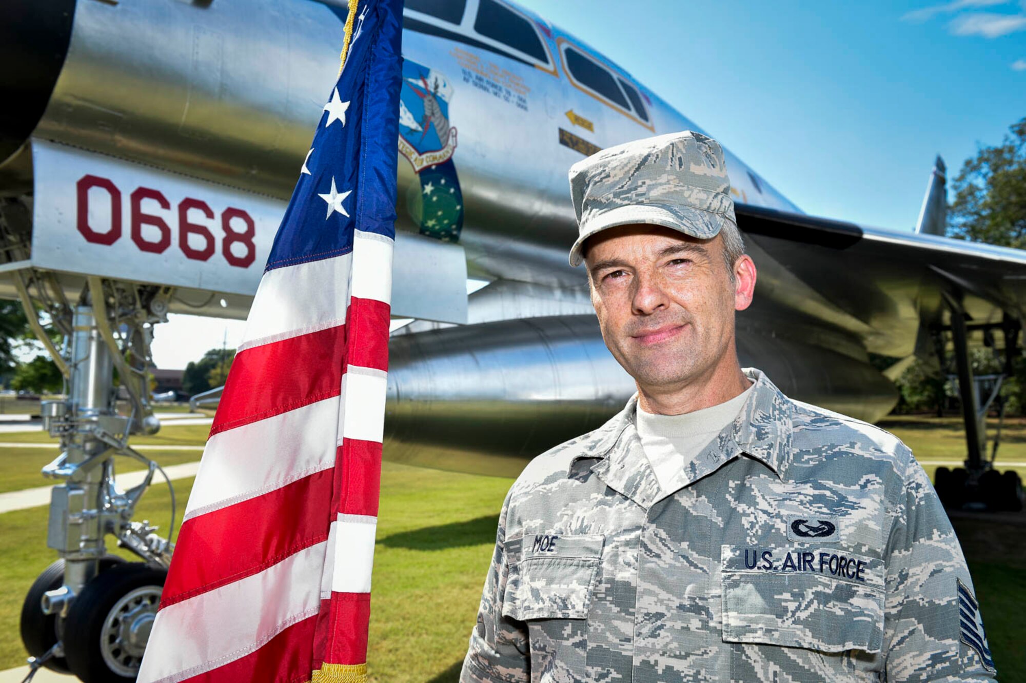 Air Force Reserve Tech. Sgt. Malcom Moe, 96th Aerial Port squadron, poses with the American flag in front of a static display aircraft after a reenlistment ceremony at Little Rock Air Force Base, Ark., Aug. 3, 2020. (U.S. Air Force Reserve photo by Senior Amn Nathan Byrnes)