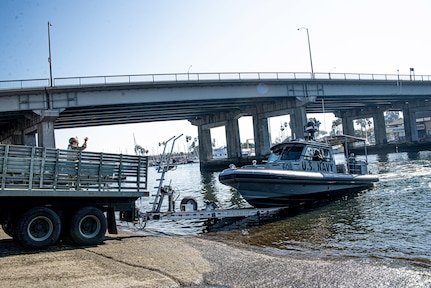 Personnel Specialist 1st Class Mary Jean Guevara, assigned to Maritime Expeditionary Security Squadron (MSRON) 11, signals a Sea Ark 34-foot patrol boat during a boat recovery in Alamitos Bay in Long Beach, California.