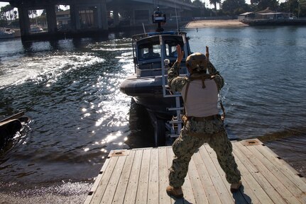 Personnel Specialist 1st Class Mary Jean Guevara, assigned to Maritime Expeditionary Security Squadron (MSRON) 11, signals a Sea Ark 34-foot patrol boat during a boat recovery in Alamitos Bay in Long Beach, California