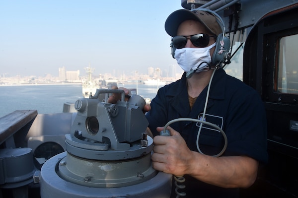 Quartermaster Seaman Wayne Bulls, assigned to the guided-missile cruiser USS Philippine Sea (CG 58), stands watch as the ship prepares to depart Bahrain following a maintenance and logistics port visit.