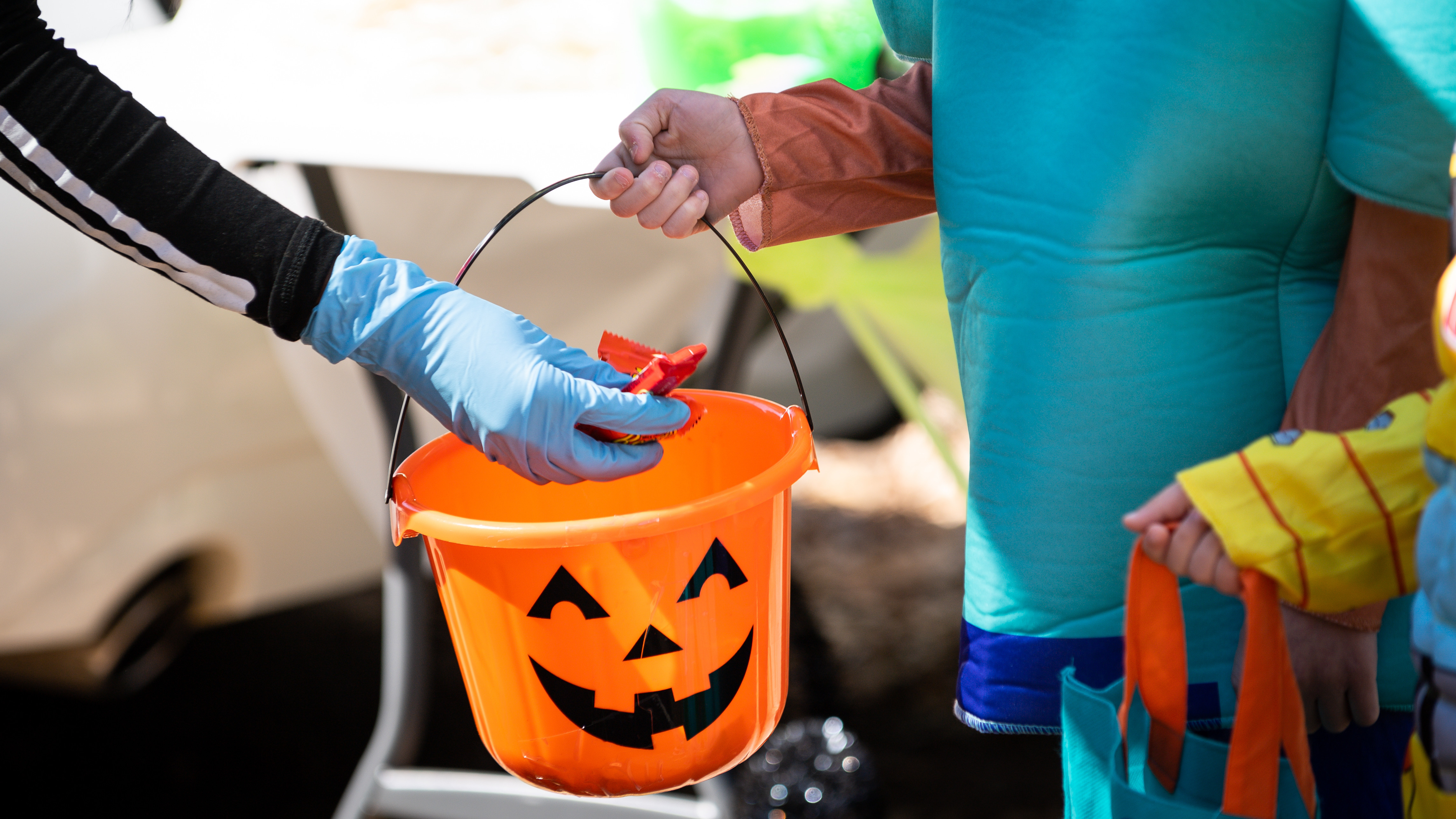 Airman Jonnica Blaylock, a Barksdale volunteer, places candy in a child’s bucket during the Trunk or Treat event at Barksdale Air Force Base, La., Oct. 31, 2020.