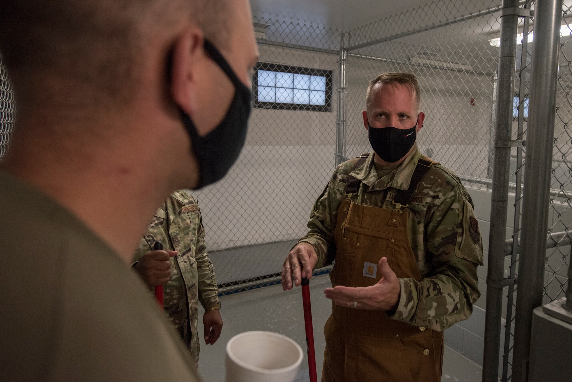 Airmen talk inside a dog kennel