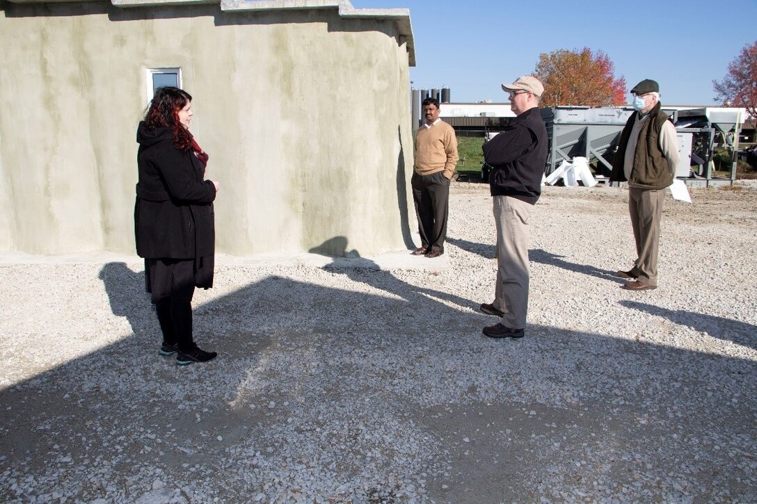 U.S. Army Engineer Research and Development Center (ERDC), Construction Engineering Research Laboratory (CERL), mechanical engineer and project lead for the Additive Construction Program and 3D Printing Megan Kreiger briefs the Principal Deputy Assistant Secretary of the Army for Installations, Energy and Environment Bryan Gossage at the ERDC Forward Operating Base-Laboratory, in Champaign, Ill., Oct. 30, 2020. Kreiger explained that the “chevron” design of the Barracks Hut construction is 2.5 times stronger than straight 3D printed concrete walls.