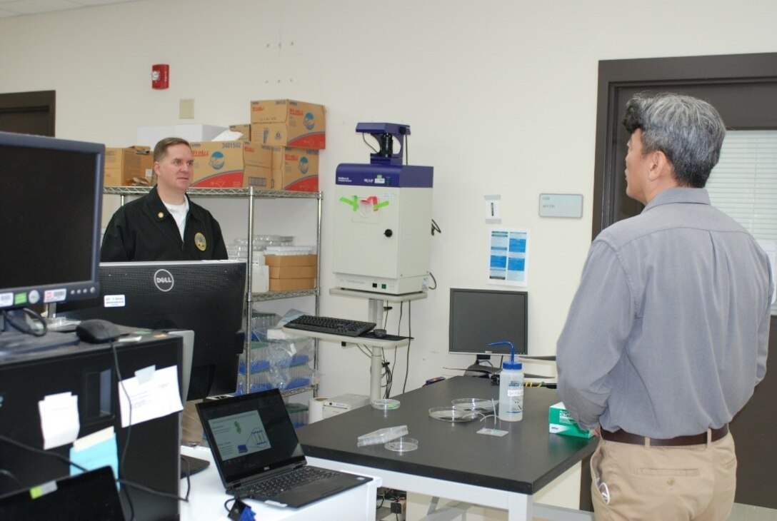 U.S. Army Engineer Research and Development Center, Construction Engineering Research Laboratory (CERL), chemist Dr. Kyoo Jo briefs the Principal Deputy Assistant Secretary of the Army for Installations, Energy and Environment Bryan Gossage on the lab’s research efforts related to synthetic biology at the CERL in Champaign, Ill., Oct. 30, 2020.