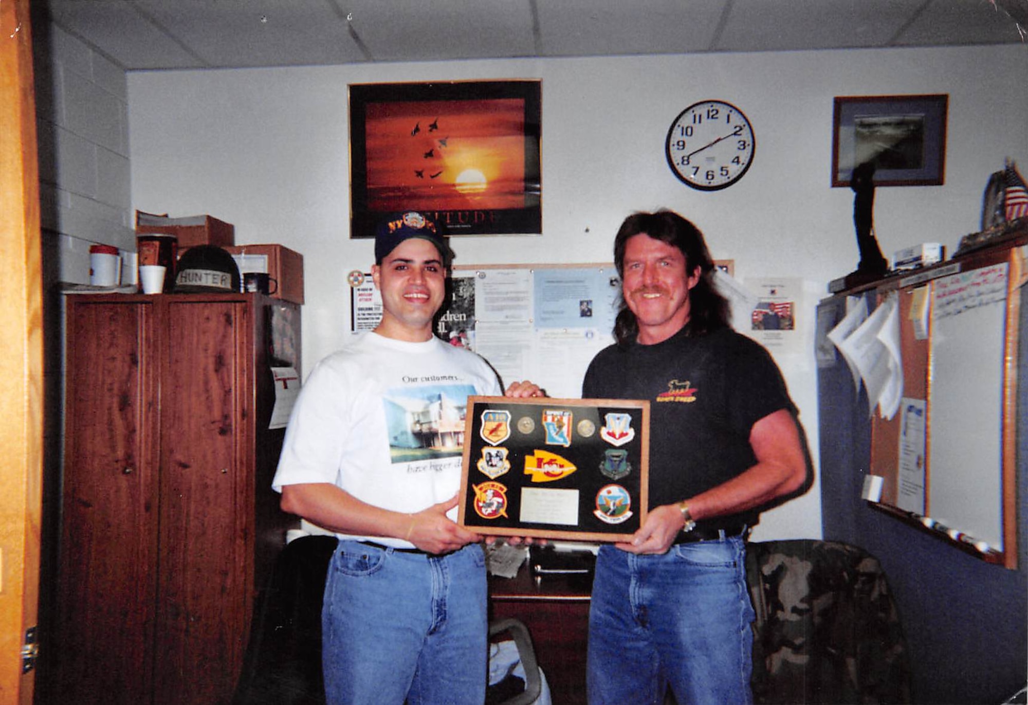 Two men stand holding a shadow box with 442d Fighter Wing and 509th Bomb Wing patches.