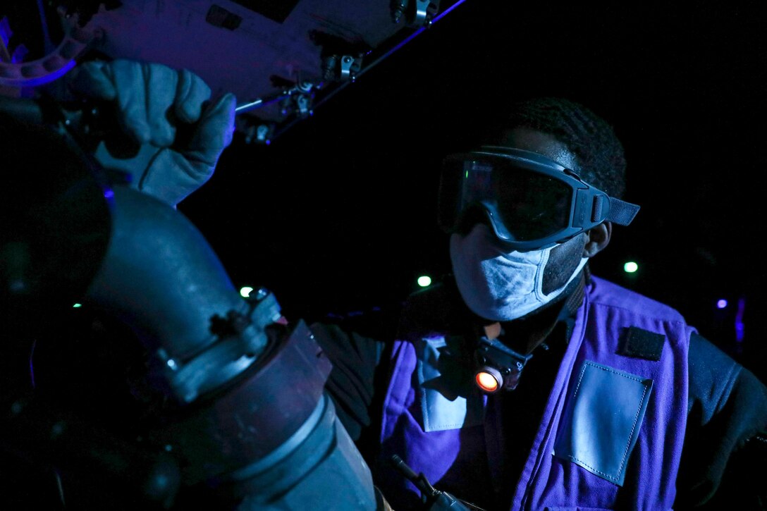 A sailor wearing protective gear fuels an aircraft.