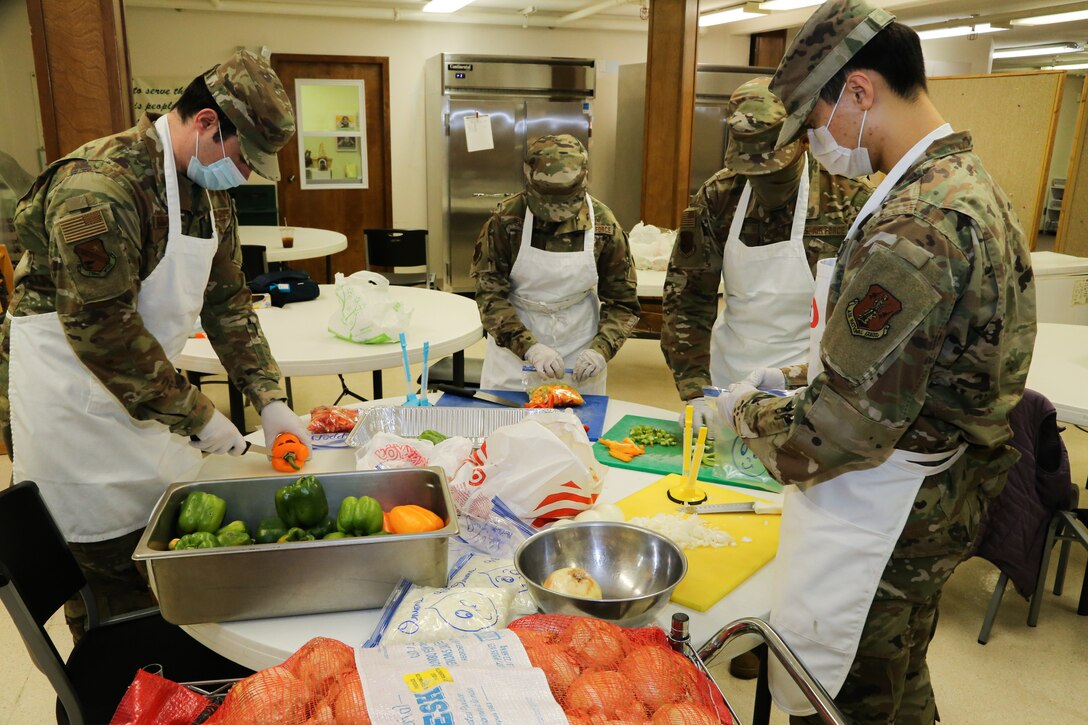(From left to right) Alaska Air National Guardsmen Tech Sgt. Brayden Van Bevera, Airman 1st Class Fionna Kelty, Tech Sgt. Allen Wilson and Senior Airman Alex Choi, all members of the 176th Force Support Flight Sustainment Services, cut fresh produce at the Five Loaves, Two Fish Kitchen in Wasilla, Alaska, Sept. 25, 2020. Food preparation is one of the many steps in creating quality meal packages for local Alaska residents in need. The Airmen have been volunteering at the kitchen since mid-August, preparing an average of 150 meals per week for local non-profit organizations. (U.S. Army National Guard photo by Sgt. Seth LaCount/Released)
