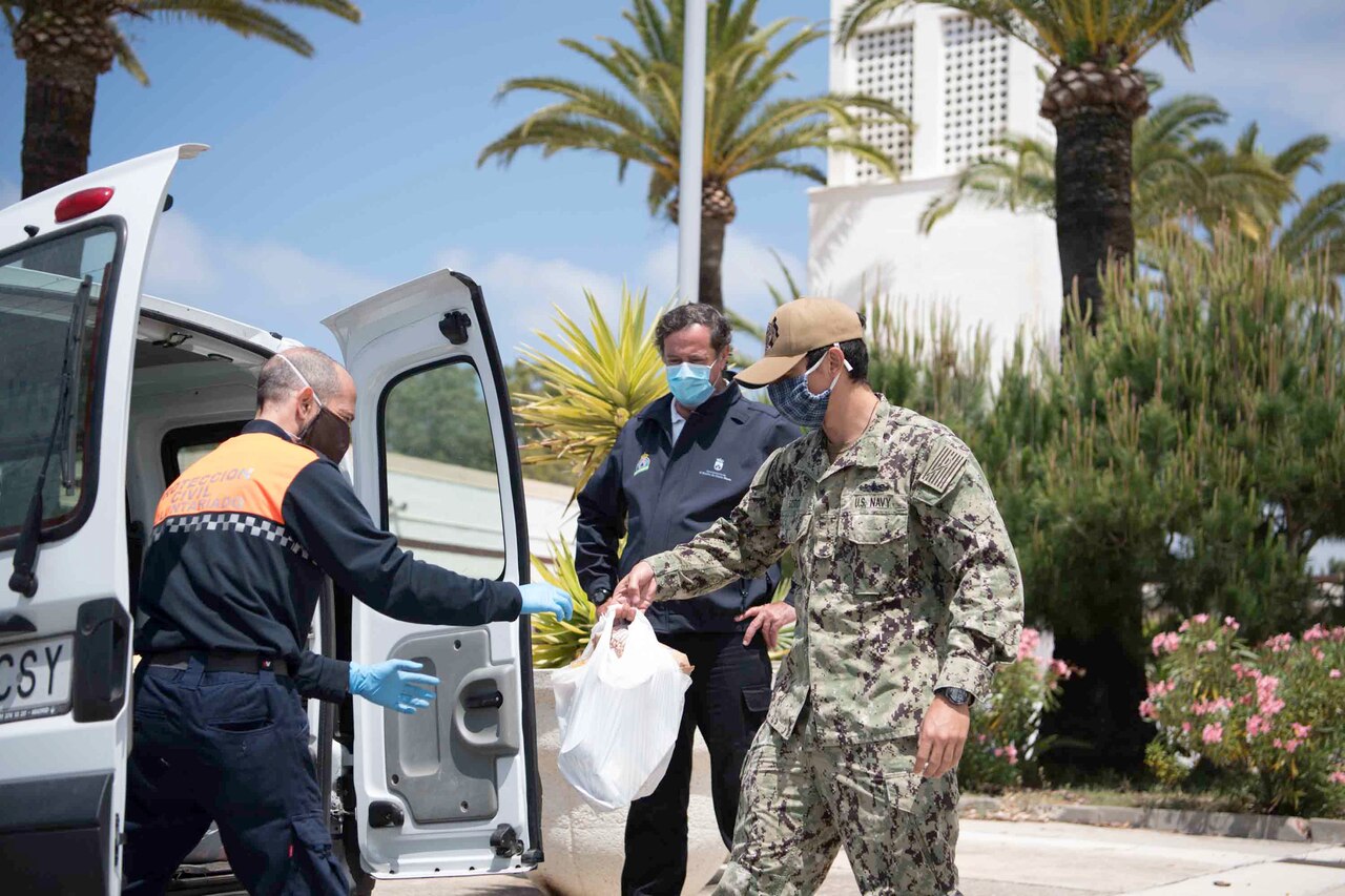 A sailor passes donations to a Spanish official.