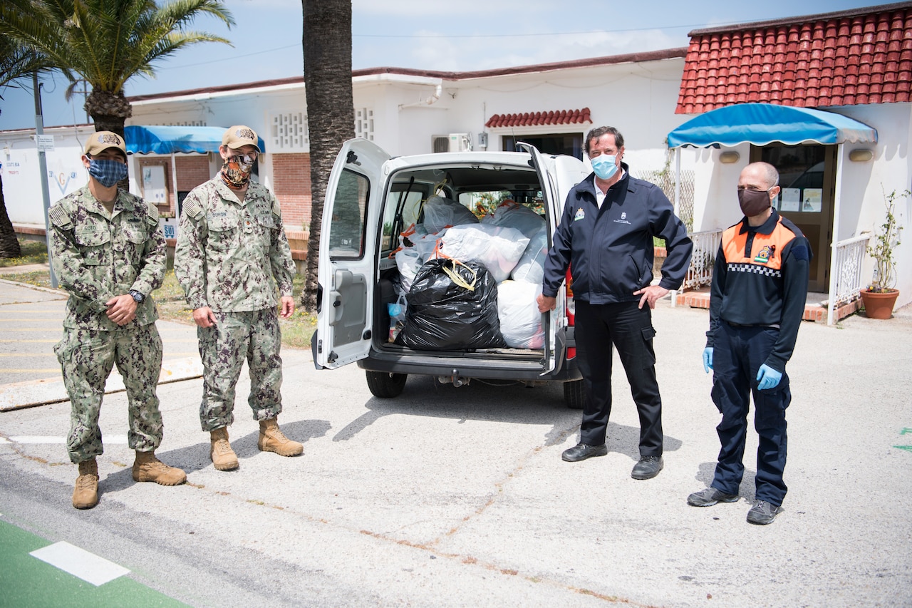 Sailors and local Spanish officials pose in front of donations.