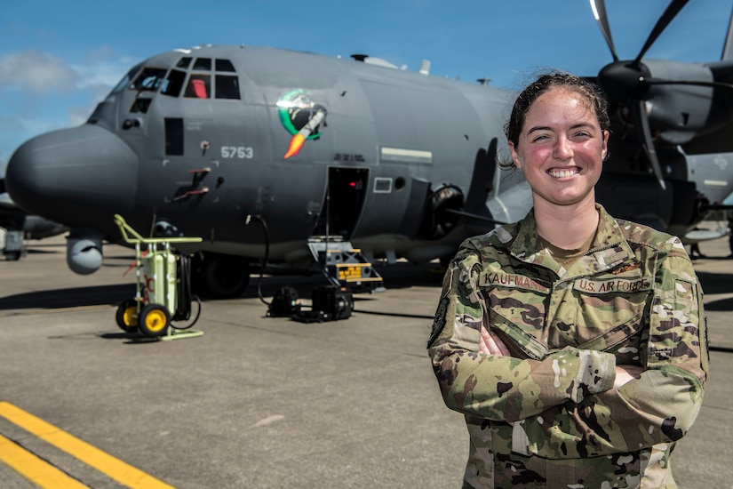 An airman poses in front of an aircraft.