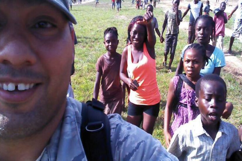 An airman takes a selfie with children.