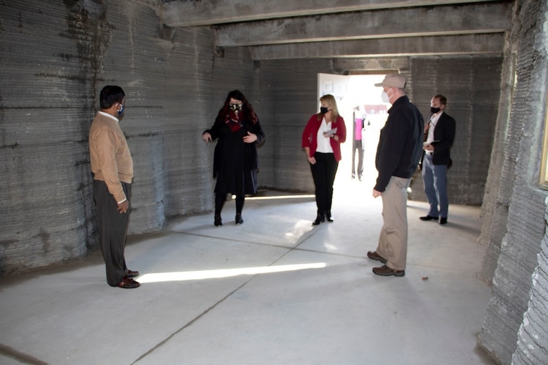 U.S. Army Engineer Research and Development Center (ERDC), Construction Engineering Research Laboratory (CERL), mechanical engineer and project lead for the Additive Construction Program and 3D Printing Megan Kreiger briefs the Principal Deputy Assistant Secretary of the Army for Installations, Energy and Environment Bryan Gossage from inside the 3D printed Barracks Hut at the ERDC, Forward Operating Base-Laboratory in Champaign, Ill., Oct. 30, 2020. The unique shape of the 3D printed walls and ceiling in the hut can withstand blasts/pressure, is stronger and can support more weight than conventional-type structures. The 3D printed concrete B-Hut reduces work hours, is more cost effective and saves valuable resources.