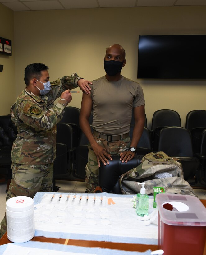 Staff Sgt. Jake Quichocho, assigned to the 379th Expeditionary Medical Group, administers the flu vaccine to the 379th Air Expeditionary Wing Command Chief, Chief Master Sgt. Kenneth Bruce, at Al Udeid Air Base, Qatar, on Nov. 3, 2020. Senior Airman Joshua Zahn, the acting NCO in charge of the allergy and immunization section, offered vaccinations in numerous work centers throughout the wing significantly improving the unit’s mission readiness by preparing service members for the upcoming flu season while preventing confusion between COVID-19 and seasonal flu symptoms. (U.S. Air Force photo by Staff Sgt. Kayla White)