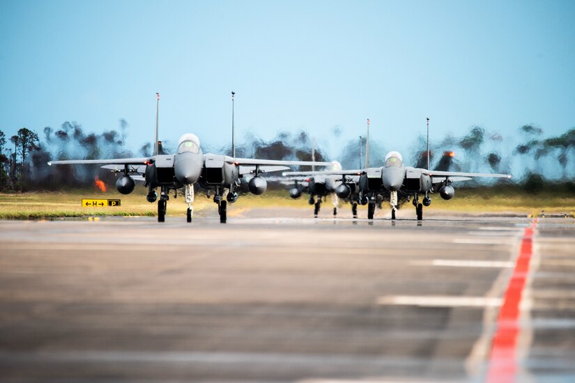 Fighter jets taxi on a runway.