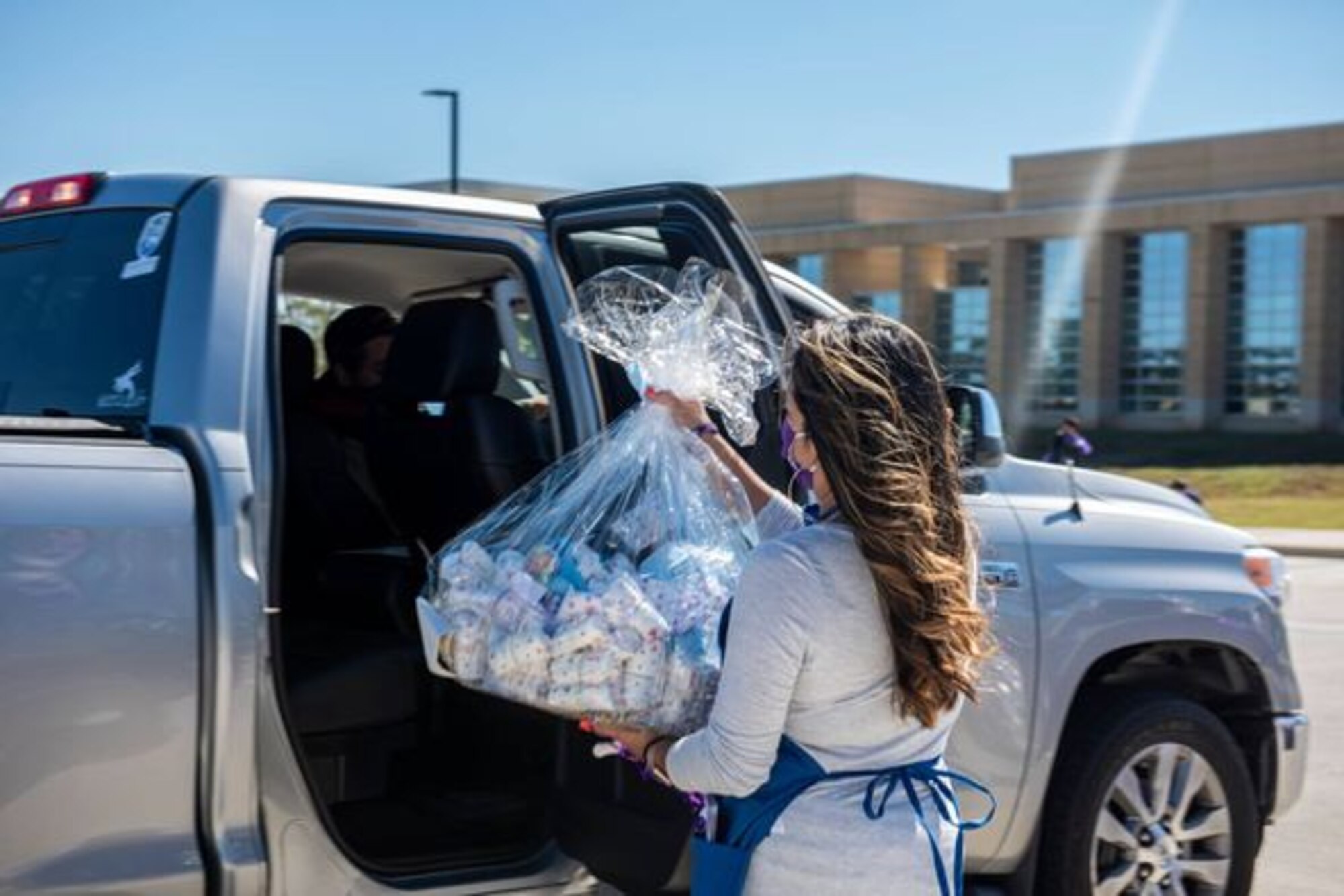 A New Parent Support Program volunteer hands a gift basket to an expecting family.