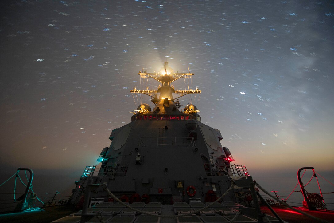 A ship steams under a starlit sky.