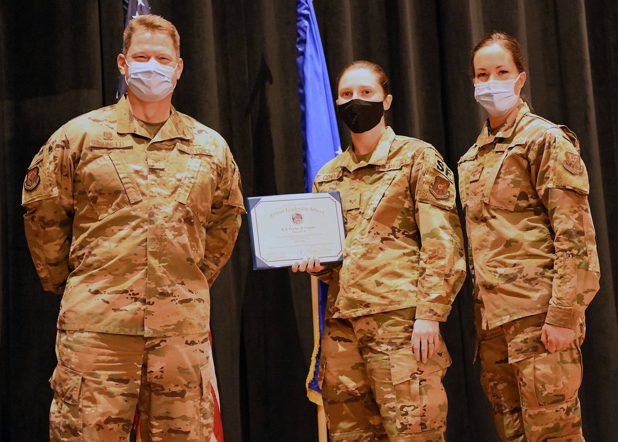 Colonel Peter Bonetti, 90th Missile Wing Commander, and Command Chief Master Sgt. Tiffany Bettisworth, present an Airman Leadership School graduate with a certificate Nov. 5 at the Base Theater on F. E. Warren Air Force Base, Wyo.