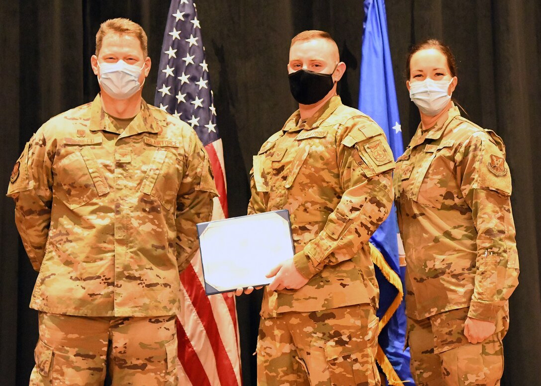 Colonel Peter Bonetti, 90th Missile Wing Commander, and Command Chief Master Sgt. Tiffany Bettisworth, present an Airman Leadership School graduate with a certificate Nov. 5 at the Base Theater on F. E. Warren Air Force Base, Wyo.