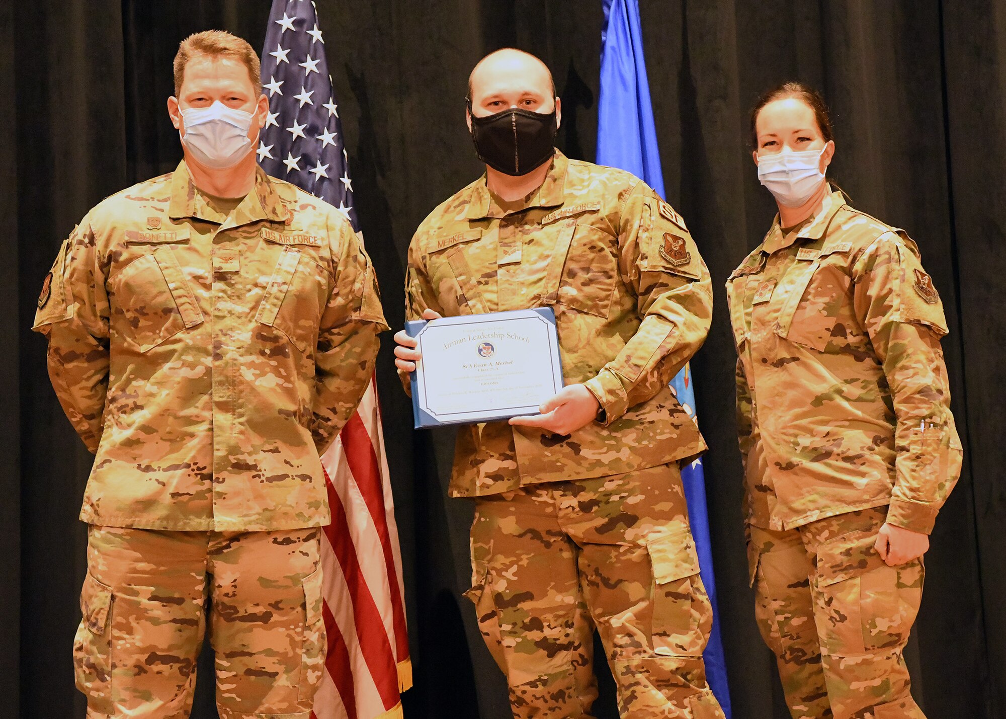 Colonel Peter Bonetti, 90th Missile Wing Commander, and Command Chief Master Sgt. Tiffany Bettisworth, present an Airman Leadership School graduate with a certificate Nov. 5 at the Base Theater on F. E. Warren Air Force Base, Wyo.