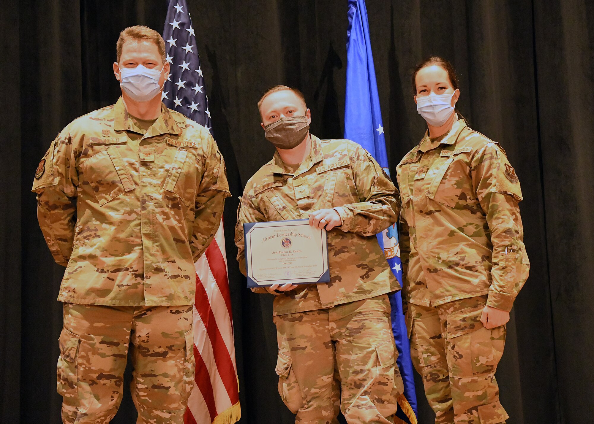 Colonel Peter Bonetti, 90th Missile Wing Commander, and Command Chief Master Sgt. Tiffany Bettisworth, present an Airman Leadership School graduate with a certificate Nov. 5 at the Base Theater on F. E. Warren Air Force Base, Wyo.