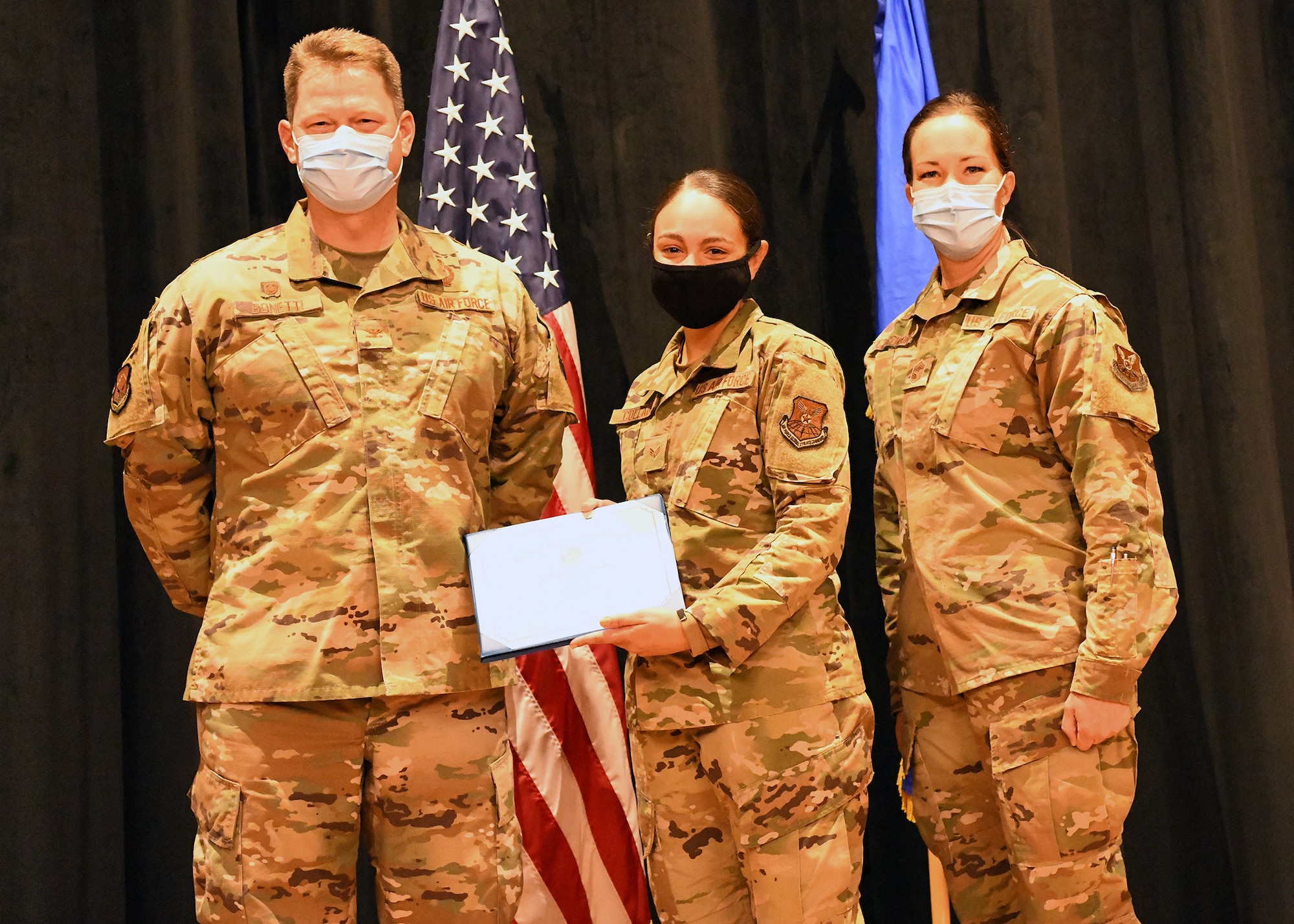 Colonel Peter Bonetti, 90th Missile Wing Commander, and Command Chief Master Sgt. Tiffany Bettisworth, present an Airman Leadership School graduate with a certificate Nov. 5 at the Base Theater on F. E. Warren Air Force Base, Wyo.