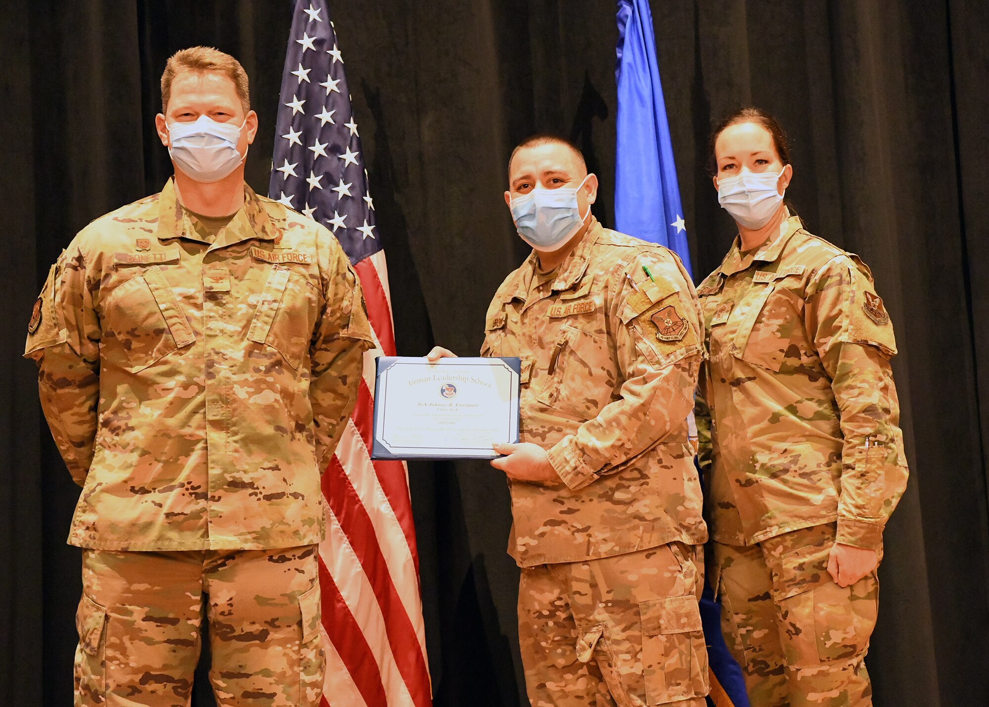 Colonel Peter Bonetti, 90th Missile Wing Commander, and Command Chief Master Sgt. Tiffany Bettisworth, present an Airman Leadership School graduate with a certificate Nov. 5 at the Base Theater on F. E. Warren Air Force Base, Wyo.