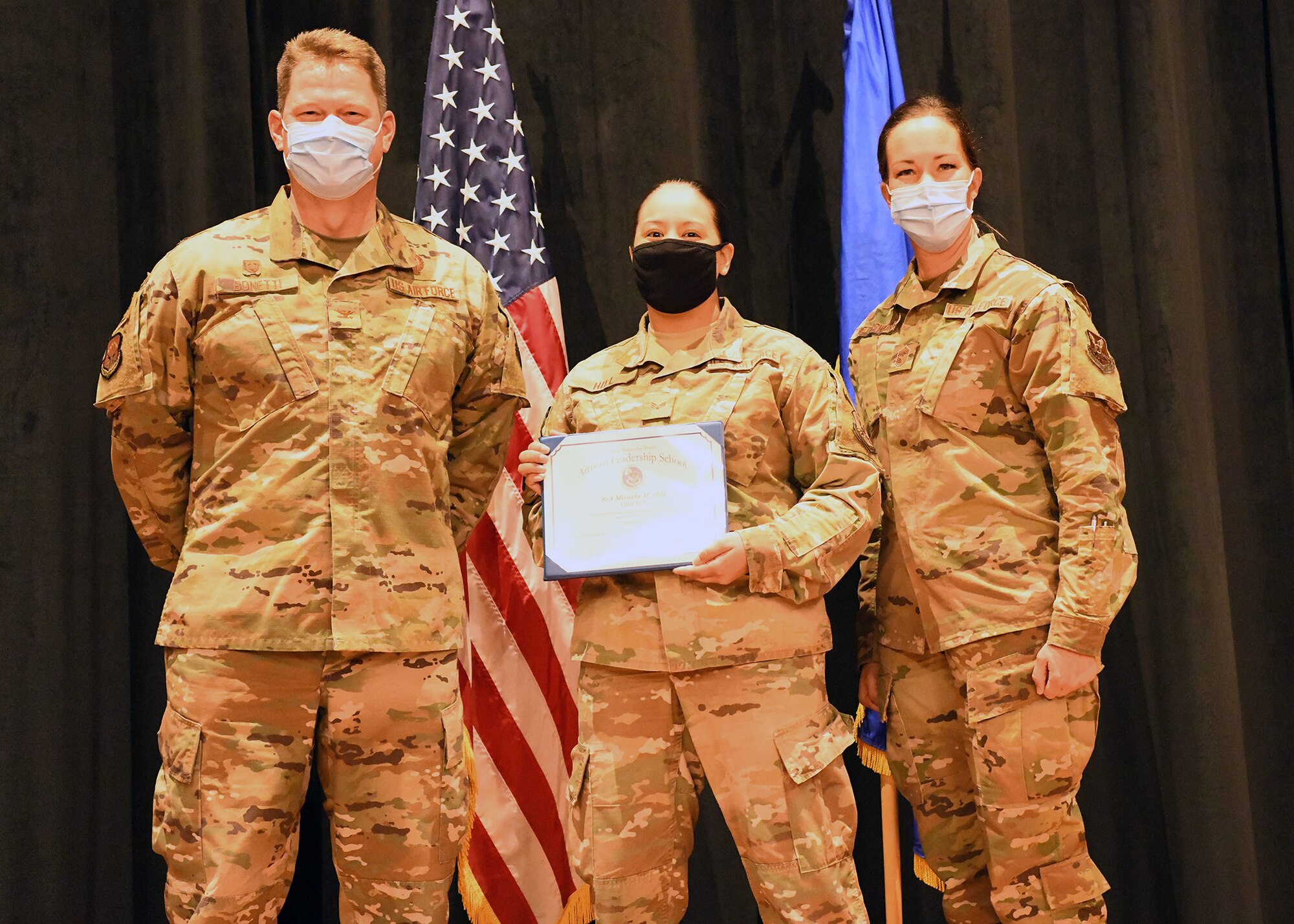 Colonel Peter Bonetti, 90th Missile Wing Commander, and Command Chief Master Sgt. Tiffany Bettisworth, present an Airman Leadership School graduate with a certificate Nov. 5 at the Base Theater on F. E. Warren Air Force Base, Wyo.