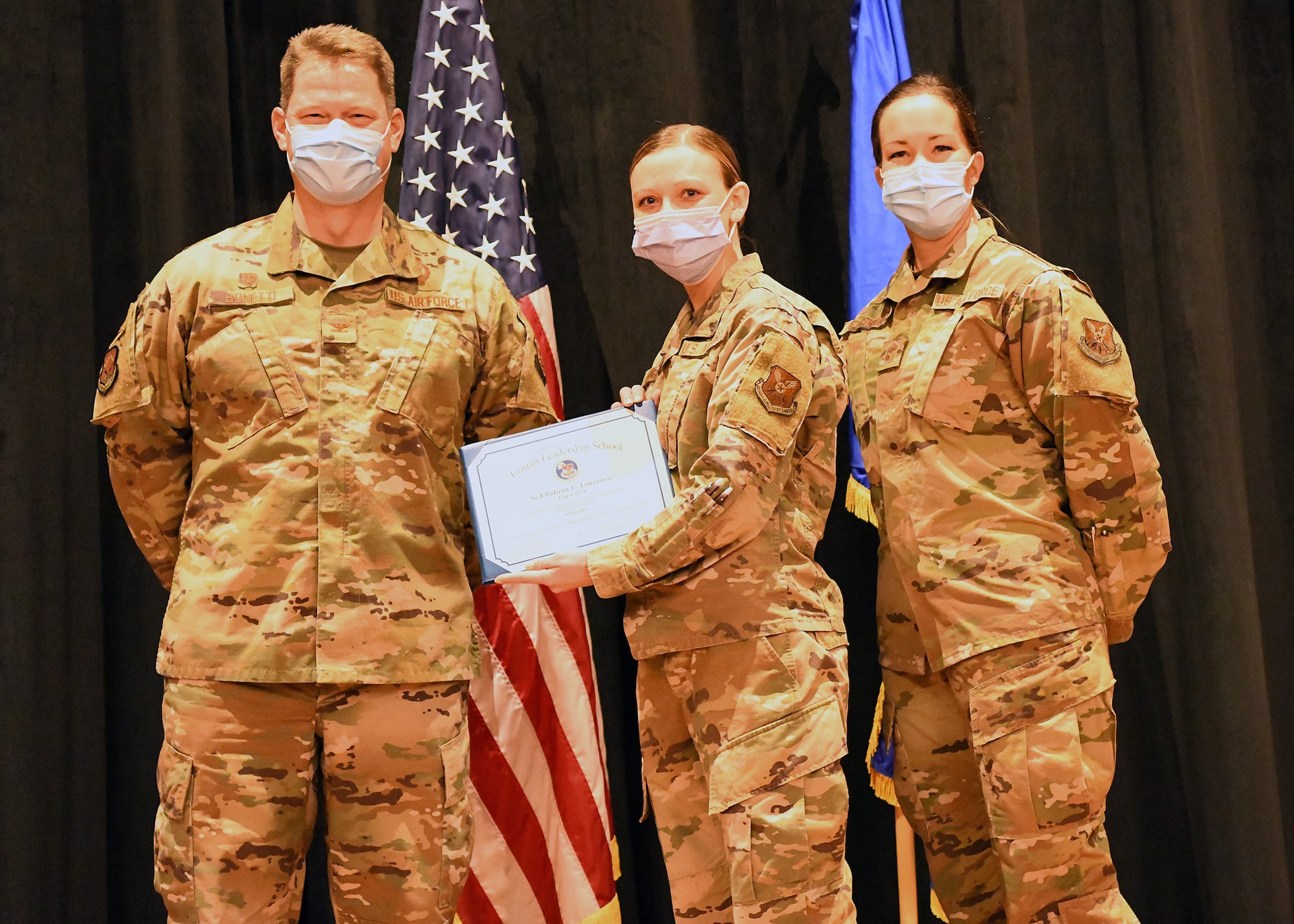 Colonel Peter Bonetti, 90th Missile Wing Commander, and Command Chief Master Sgt. Tiffany Bettisworth, present an Airman Leadership School graduate with a certificate Nov. 5 at the Base Theater on F. E. Warren Air Force Base, Wyo.