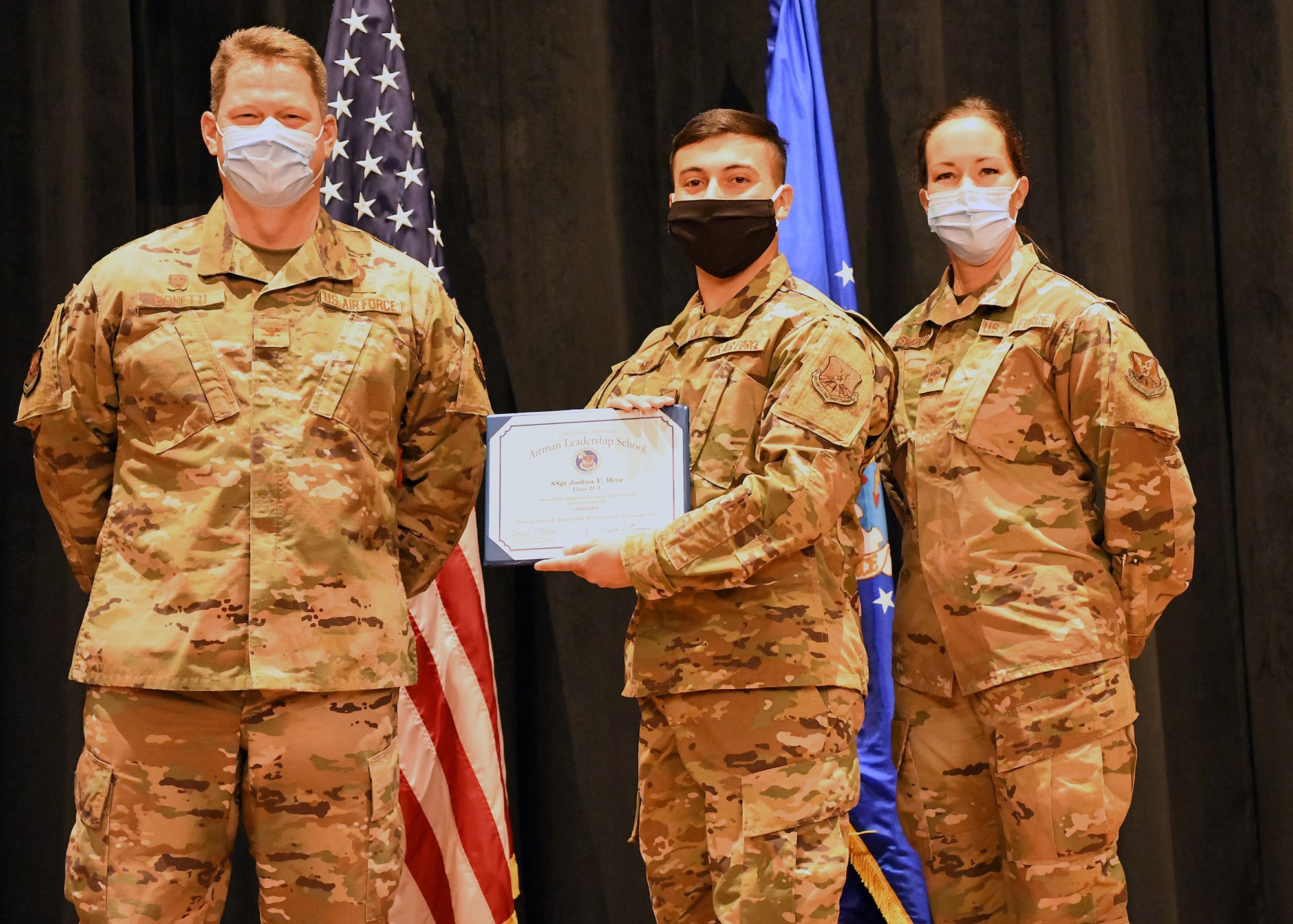 Colonel Peter Bonetti, 90th Missile Wing Commander, and Command Chief Master Sgt. Tiffany Bettisworth, present an Airman Leadership School graduate with a certificate Nov. 5 at the Base Theater on F. E. Warren Air Force Base, Wyo.