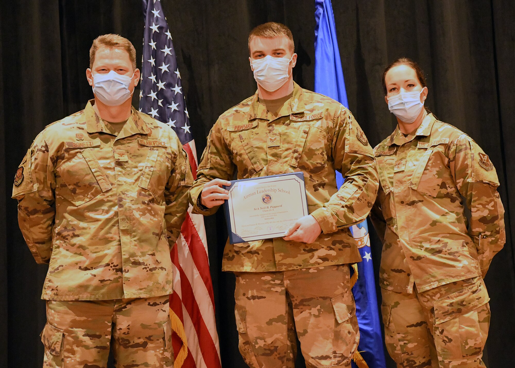 Colonel Peter Bonetti, 90th Missile Wing Commander, and Command Chief Master Sgt. Tiffany Bettisworth, present an Airman Leadership School graduate with a certificate Nov. 5 at the Base Theater on F. E. Warren Air Force Base, Wyo.