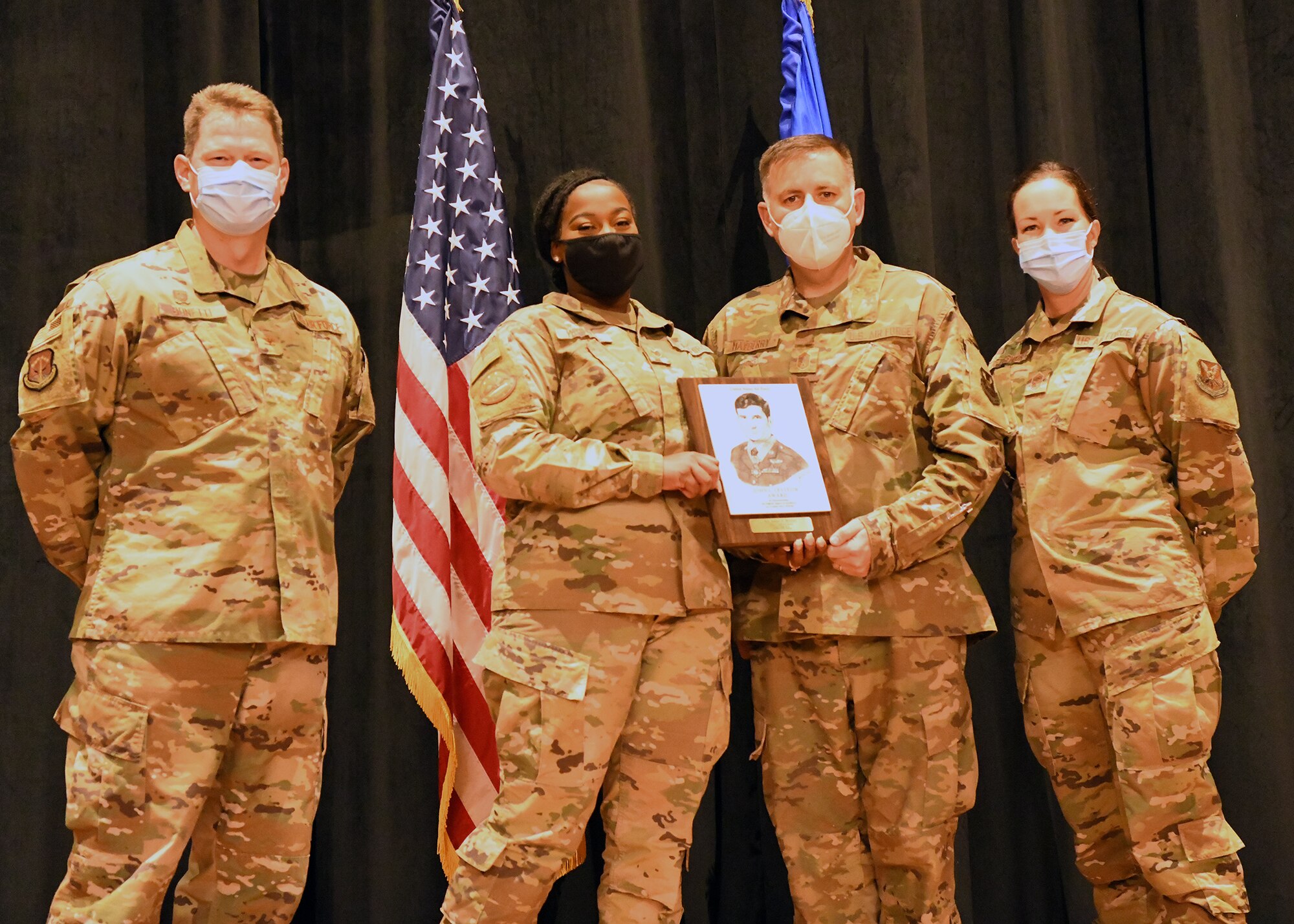 Colonel Peter Bonetti, 90th Missile Wing Commander, and Command Chief Master Sgt. Tiffany Bettisworth, present an Airman Leadership School graduate with a certificate Nov. 5 at the Base Theater on F. E. Warren Air Force Base, Wyo.