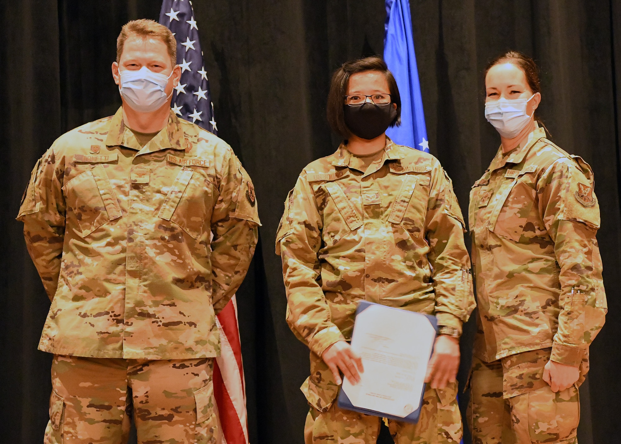 Colonel Peter Bonetti, 90th Missile Wing Commander, and Command Chief Master Sgt. Tiffany Bettisworth, present an Airman Leadership School graduate with a certificate Nov. 5 at the Base Theater on F. E. Warren Air Force Base, Wyo.