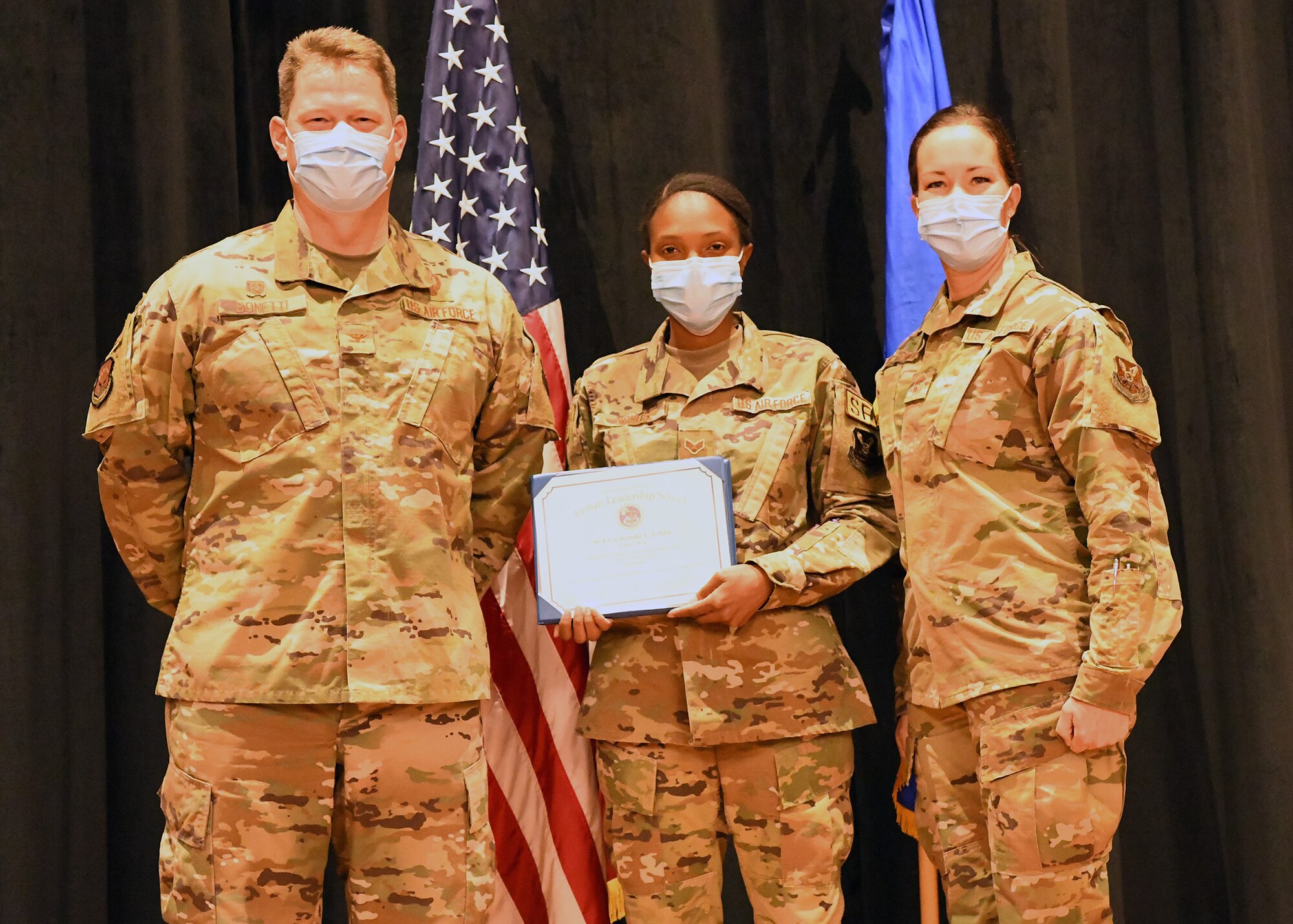 Colonel Peter Bonetti, 90th Missile Wing Commander, and Command Chief Master Sgt. Tiffany Bettisworth, present an Airman Leadership School graduate with a certificate Nov. 5 at the Base Theater on F. E. Warren Air Force Base, Wyo.