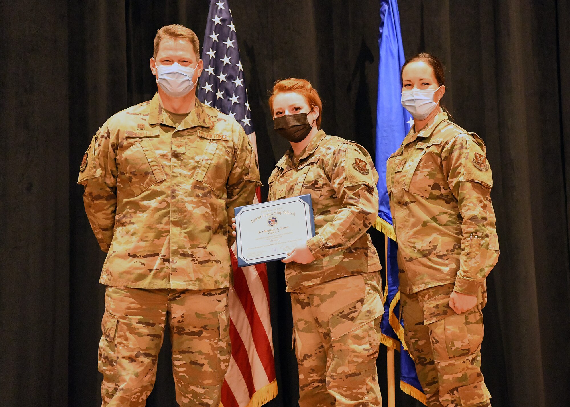 Colonel Peter Bonetti, 90th Missile Wing Commander, and Command Chief Master Sgt. Tiffany Bettisworth, present an Airman Leadership School graduate with a certificate Nov. 5 at the Base Theater on F. E. Warren Air Force Base, Wyo.