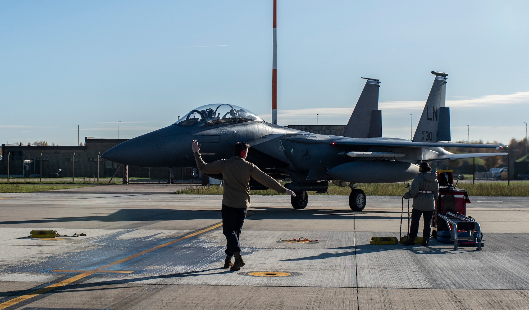 A crew chief assigned to the 48th Aircraft Maintenance Unit marshalls an F-15E Strike Eagle onto the apron after a training sortie in support of exercise Crimson Warrior at Royal Air Force Lakenheath, England, Nov. 6, 2020.  Multi-domain integration exercises like Crimson Warrior strengthen NATO interoperability and test high-end capabilities in a contested, degraded, and operationally limited environment. (U.S. Air Force photo by Airman 1st Class Jessi Monte)