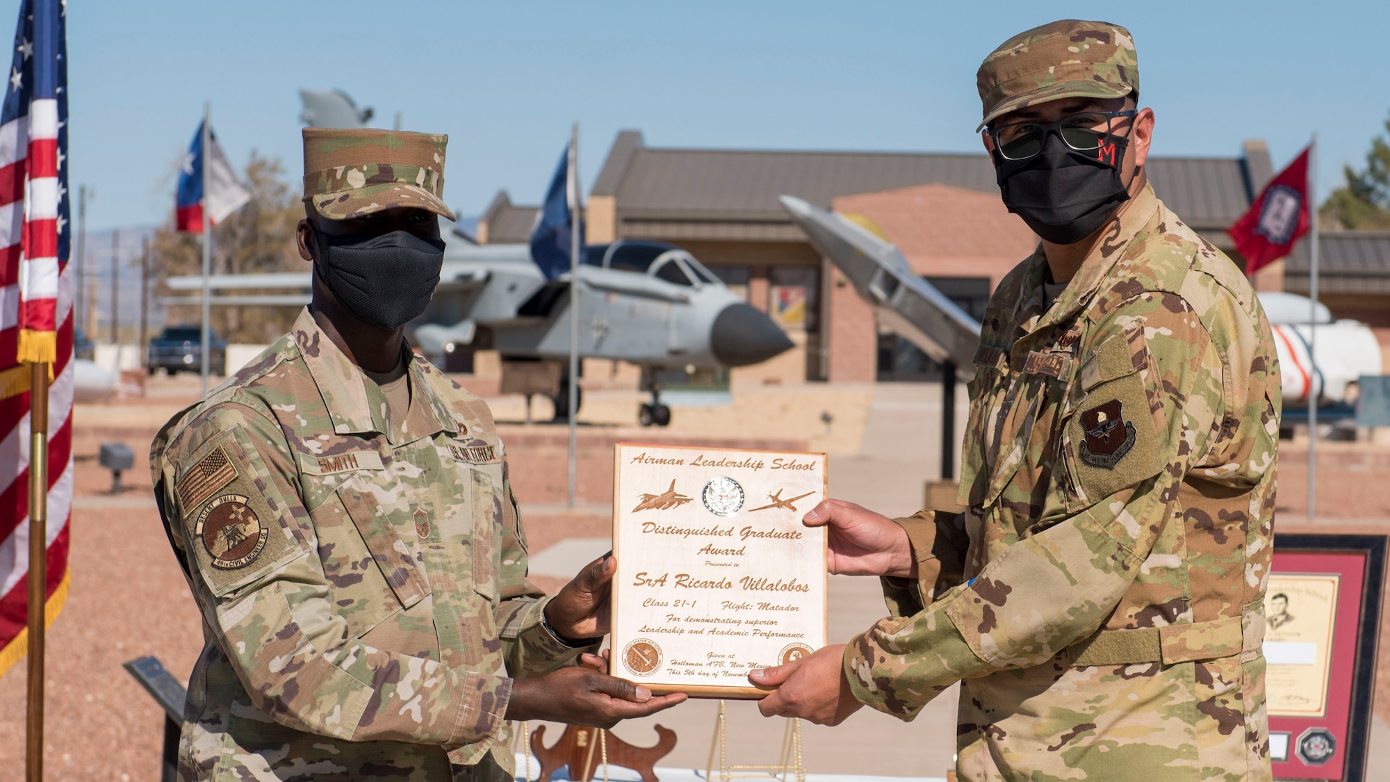 Senior Airman Ricardo Villalobos, right, Airman Leadership School graduate, accepts the distinguished graduate award during the graduation of ALS class 21-1, Nov. 5, 2020, on Holloman Air Force Base, New Mexico. The distinguished graduate award is presented to the top ten-percent of graduates for their performance in academic evaluations and demonstration of leadership. (U.S. Air Force photo by Staff Sgt. Christine Groening)